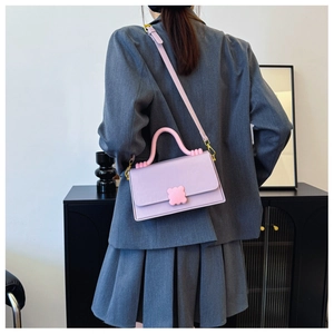 Detail of lavender contrast handbag with pink wavy handle and floral clasp on model
