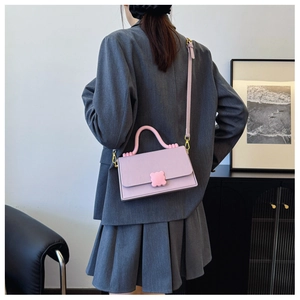 Detail of a lavender crossbody bag with a pink floral buckle and thick top handle