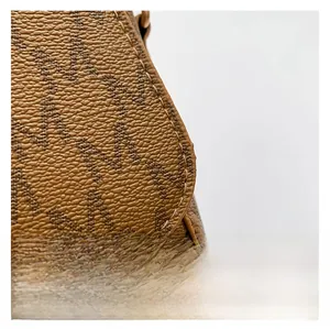 Detailed close-up of brown textured leather bag featuring repeat letter M monogram pattern