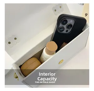Detail view showing interior capacity of a white leather bag with phone and skincare bottle
