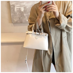 Sac à bandoulière blanc en similicuir avec logo triangulaire porté par un mannequin
