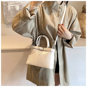 Détail d'un sac à bandoulière en cuir crème avec logo triangulaire et boucle décorative