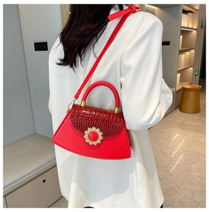 Detail der roten Handtasche mit Krokostruktur und goldener Sonnenschnalle am Model