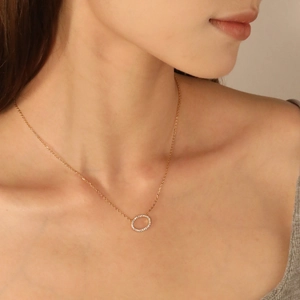 Gros plan d'un collier avec pendentif cercle en or rose serti de cristaux sur un mannequin