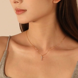 Collier croix en acier inoxydable rose doré avec pavé de zircons porté par un mannequin