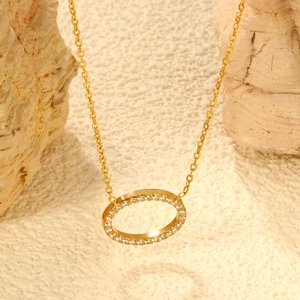 Vue macro d'un collier pendentif ovale doré avec zircons sur un fond de pierre texturé