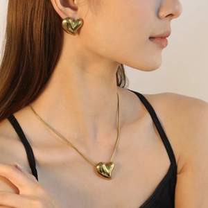 Polished gold 3D heart jewelry set including necklace and earrings on model
