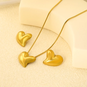 3D heart jewelry set with gold snake chain and matching earrings on a warm stone base