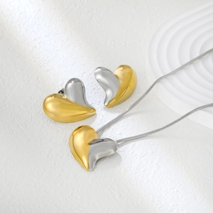 Detail of two-tone heart jewelry set featuring gold and silver finish on a white stand
