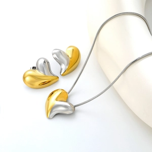 Detail of two-tone heart jewelry set with polished gold and silver finish on white background