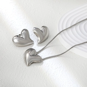Macro shot of silver stainless steel heart earrings and pendant with snake chain
