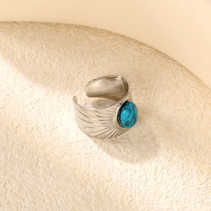 Macro shot of silver wide band ring with bohemian radial texture and turquoise stone
