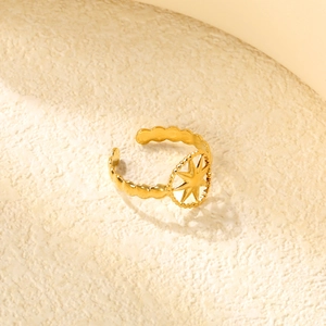 Macro detail of gold adjustable star ring with unique beaded band on beige texture