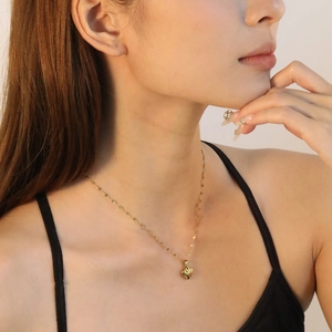 Elegante collana con ciondolo a cuore dorato su catena a grani indossata da una modella