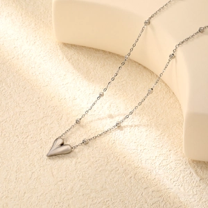 Dettaglio del ciondolo a cuore argento su catena a sfere con finitura a specchio