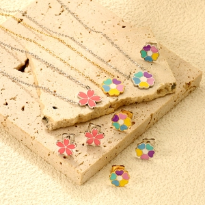 Dettaglio macro di collane e orecchini a fiori di ciliegio su base in pietra beige