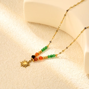 Detailed macro view of the gold sun pendant with colorful beads and sunburst design