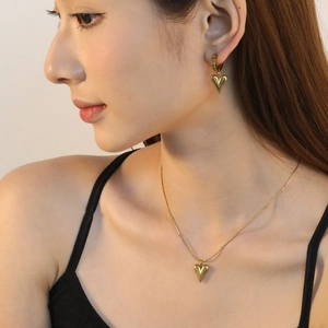 Parure de bijoux cœur dorée comprenant un collier poli et des boucles d'oreilles sur modèle