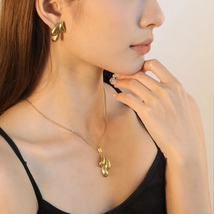 Parure bijoux dorée avec collier et boucles d'oreilles pendantes portée par un mannequin