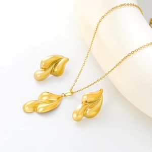 Parure collier et boucles d'oreilles en feuilles dorées sur présentoir blanc élégant