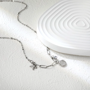 Détail macro du collier argenté avec pendentifs en forme de coquillage et d'étoile