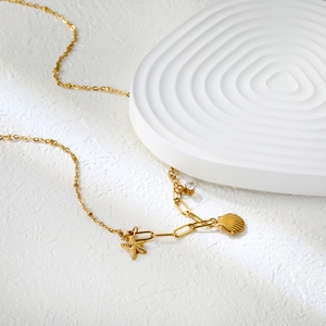 Détail du collier avec pendentif étoile de mer et coquillage en or 18k sur socle