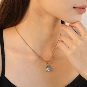 Gold chain necklace featuring a blue-grey waterdrop stone sun pendant on a model