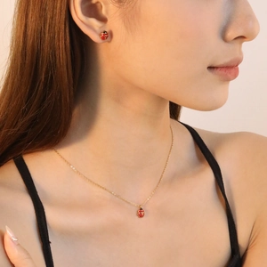 Cute red ladybug jewelry set featuring a gold-toned necklace and matching stud earrings