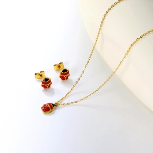 Detailed view of red ladybug jewelry set with necklace and stud earrings in gold finish