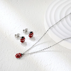 Detail shot of ladybug jewelry set featuring red enamel necklace and matching stud earrings