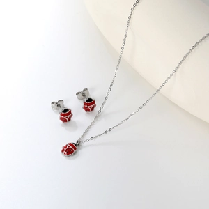 Detail of red enamel ladybug necklace and stud earrings set with polished silver finish