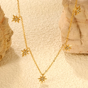 Detailed view of gold necklace with five star pendants featuring small white zircons