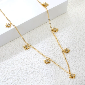 Golden cross chain necklace with sparkling star pendants on a minimalist white stand