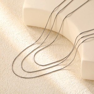 Detailed view of layered silver stainless steel snake chains on minimalist display