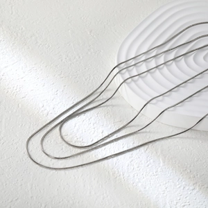 Macro detail of multi-layered silver snake chains with minimalist stainless steel texture