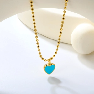 Détail du pendentif cœur bleu sur une chaîne à billes dorée avec support minimaliste
