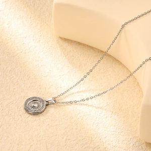Gros plan détaillé d'un collier pendentif pièce de monnaie soleil argenté sur pierre