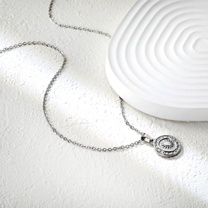 Vue détaillée d'un collier avec pendentif soleil argenté sur un support en pierre