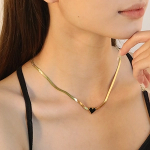 Collier chaîne serpent plaqué or avec pendentif cœur noir porté par un mannequin