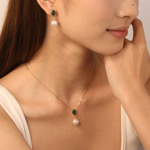 Elegant gold necklace and earrings set with green teardrop gemstones and white pearls