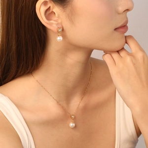 Detail of gold heart zircon and pearl necklace set worn by a model in soft light