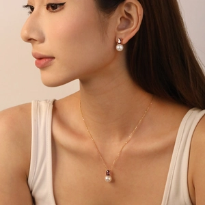 Model wearing pearl earrings and necklace set with purple zircon in gold plating