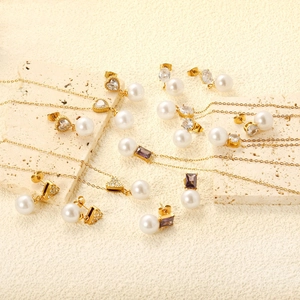 Detailed set of gold jewelry with pearls, heart-shaped zircons and purple gemstones on stone
