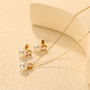 Detailed close-up of gold heart stud earrings and pearl necklace jewelry set