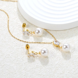 Detail of gold zircon and pearl jewelry set featuring heart stud earrings and necklace