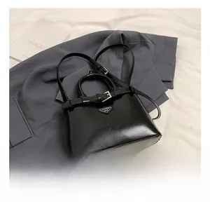 Détail du sac bandoulière noir avec boucles métalliques et plaque logo triangle de mode