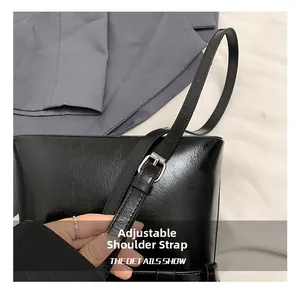 Détail de la boucle réglable sur un sac cabas en cuir noir à texture cirée