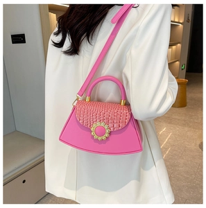 Detail der rosa Kroko-Handtasche mit goldenem Sonnenverschluss am weißen Anzug der Frau