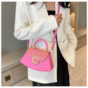Detail der rosa Handtasche mit Krokoprägung und goldener Schnalle auf weißem Blazer