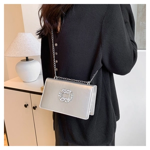 Detail of silver square chain bag featuring a luxury rhinestone buckle on model